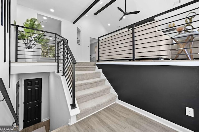 staircase with hardwood / wood-style floors and ceiling fan