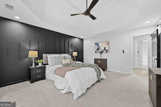 carpeted bedroom featuring ceiling fan and a tray ceiling