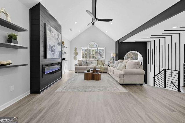 living room featuring ceiling fan, a fireplace, high vaulted ceiling, and light hardwood / wood-style flooring