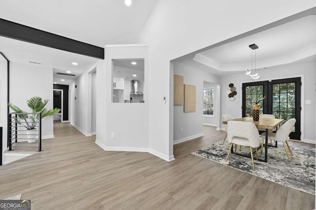 dining room with a notable chandelier, a tray ceiling, ornamental molding, and light hardwood / wood-style floors