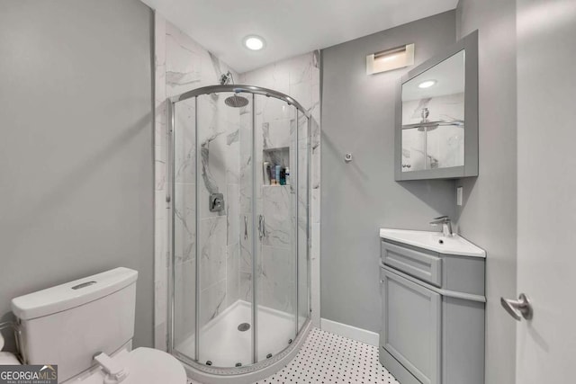 bathroom featuring vanity, a shower with shower door, and toilet