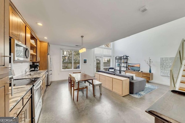 kitchen featuring stainless steel appliances, decorative light fixtures, sink, and backsplash