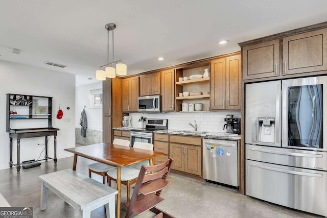 kitchen featuring sink, tasteful backsplash, light stone counters, hanging light fixtures, and appliances with stainless steel finishes