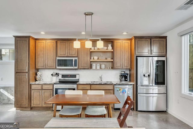 kitchen featuring appliances with stainless steel finishes, sink, backsplash, hanging light fixtures, and light stone countertops