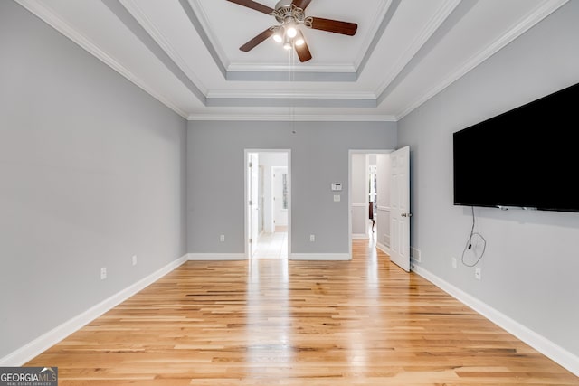 unfurnished living room featuring ornamental molding, ceiling fan, light wood-type flooring, and a tray ceiling