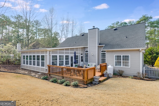 back of house featuring a sunroom, a deck, and a lawn