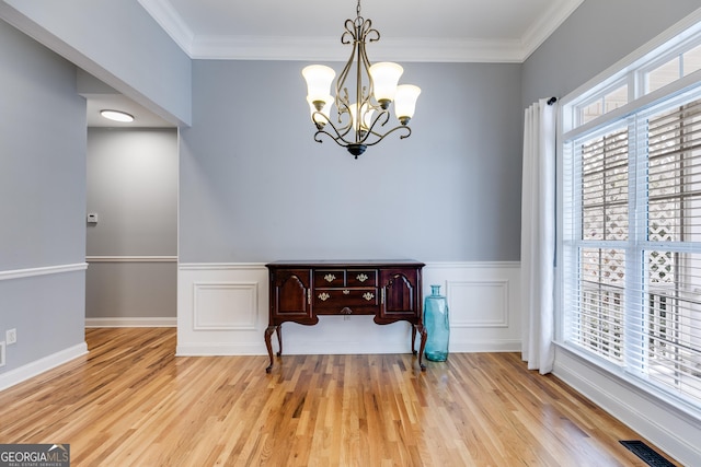 dining space with ornamental molding, a notable chandelier, and light hardwood / wood-style floors