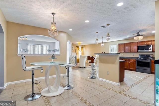 kitchen featuring hanging light fixtures, light tile patterned flooring, appliances with stainless steel finishes, and a textured ceiling