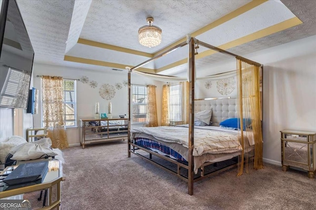 bedroom featuring a tray ceiling, a chandelier, carpet floors, and a textured ceiling