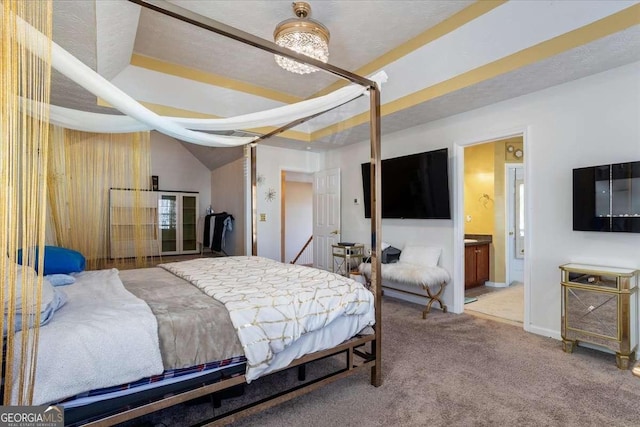 carpeted bedroom with ensuite bath and vaulted ceiling