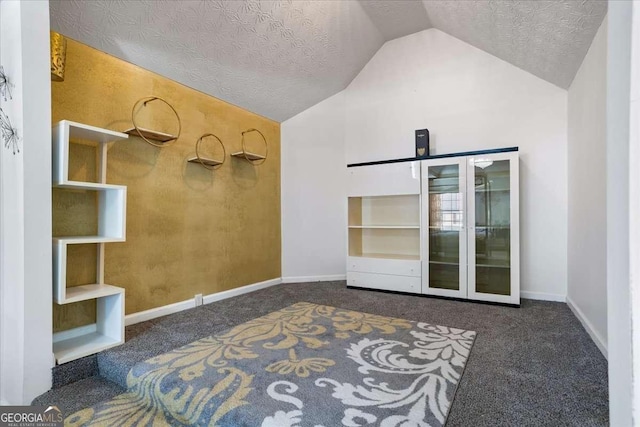 interior space with dark carpet, vaulted ceiling, and a textured ceiling