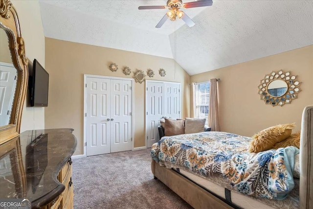 carpeted bedroom with multiple closets, vaulted ceiling, ceiling fan, and a textured ceiling