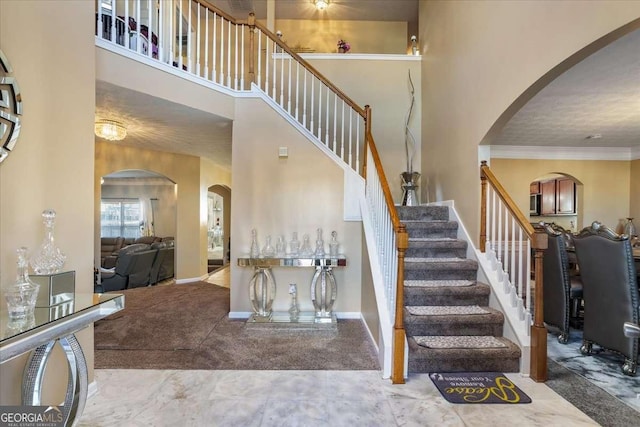 stairway with a high ceiling, ornamental molding, and carpet flooring