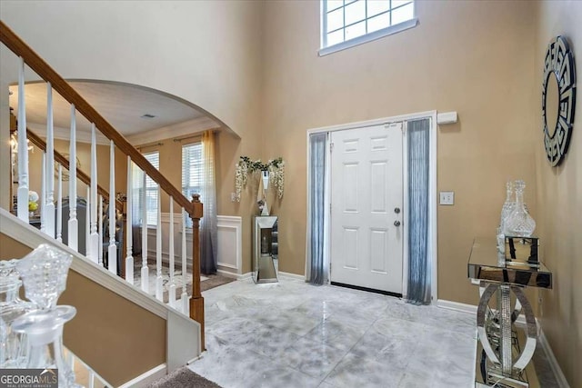 foyer with crown molding, plenty of natural light, and a high ceiling