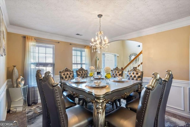 dining area featuring crown molding, carpet floors, a textured ceiling, and a notable chandelier