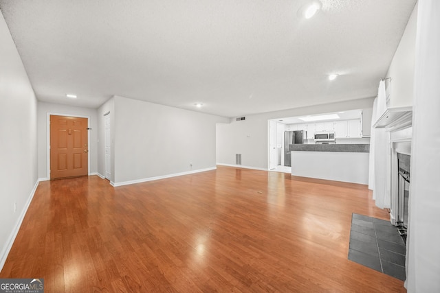 23 Chelsea Ct, Avondale Estates, GA 30002 - unfurnished living room with visible vents, a tiled fireplace, baseboards, and light wood-style floors