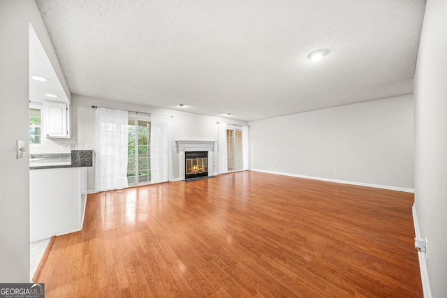23 Chelsea Ct, Avondale Estates, GA 30002 - unfurnished living room with a fireplace with flush hearth, light wood-style floors, a textured ceiling, and baseboards