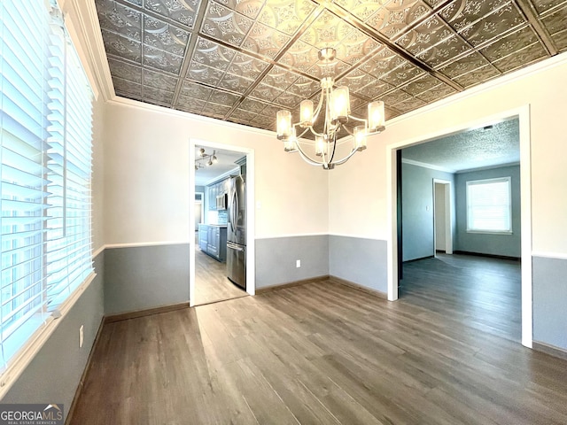 unfurnished room with hardwood / wood-style floors, ornamental molding, and a chandelier