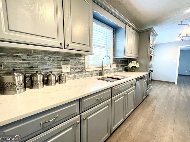 kitchen with sink, gray cabinetry, wood-type flooring, stainless steel appliances, and decorative backsplash