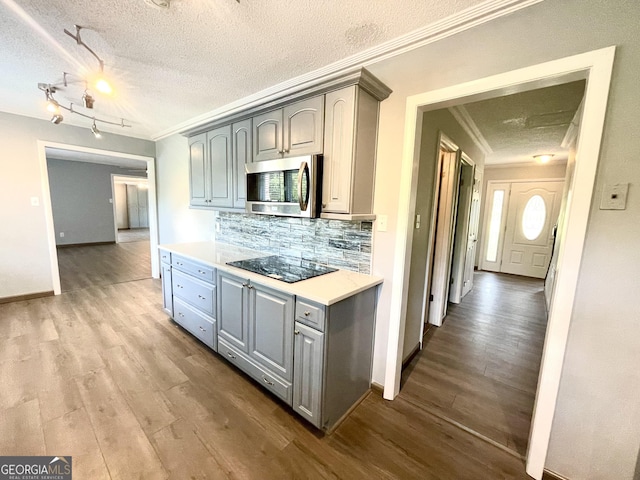 kitchen with crown molding, light hardwood / wood-style flooring, gray cabinets, backsplash, and black electric stovetop