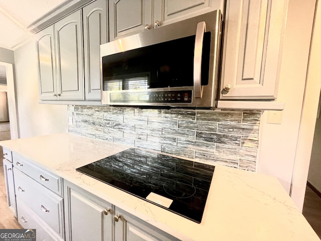 kitchen featuring tasteful backsplash, black electric stovetop, and light stone countertops