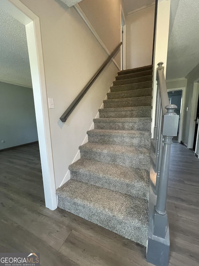 stairway featuring hardwood / wood-style flooring, crown molding, and a textured ceiling