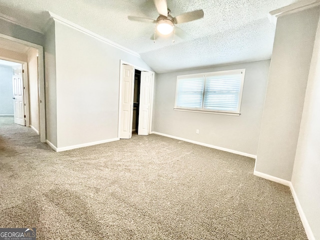 unfurnished bedroom with vaulted ceiling, a textured ceiling, a closet, ceiling fan, and carpet