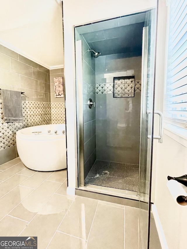 bathroom with a shower with door, tile walls, and tile patterned floors