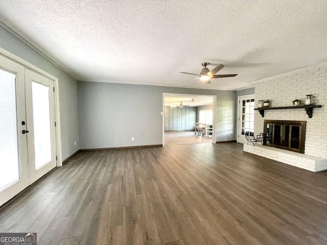 unfurnished living room with dark hardwood / wood-style flooring, crown molding, a fireplace, and french doors