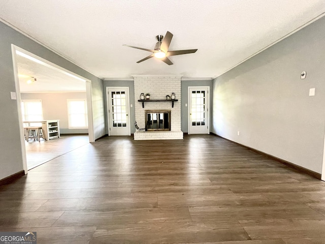 unfurnished living room featuring a fireplace, dark wood-type flooring, ornamental molding, and ceiling fan