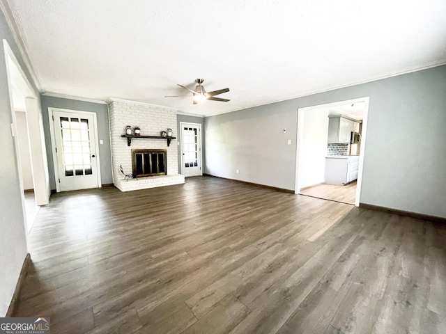 unfurnished living room featuring ornamental molding, a brick fireplace, hardwood / wood-style floors, and ceiling fan