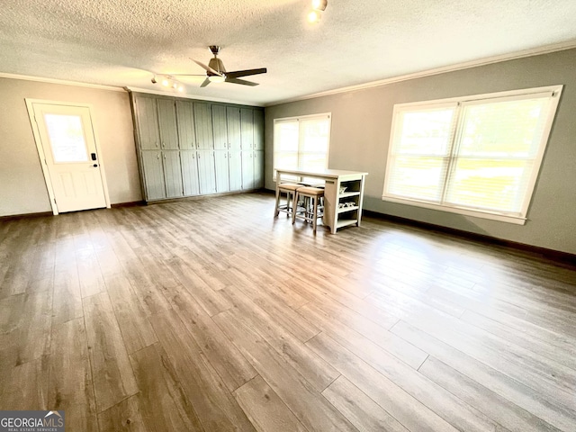 unfurnished dining area featuring crown molding, a textured ceiling, and light wood-type flooring