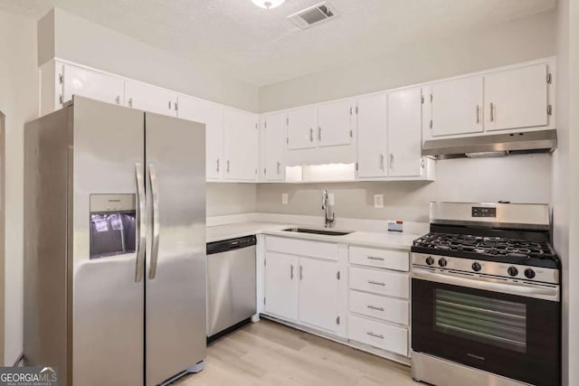 kitchen featuring a sink, visible vents, light countertops, under cabinet range hood, and appliances with stainless steel finishes