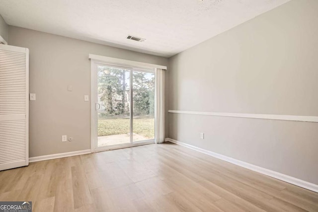 unfurnished room featuring light wood finished floors, baseboards, and visible vents