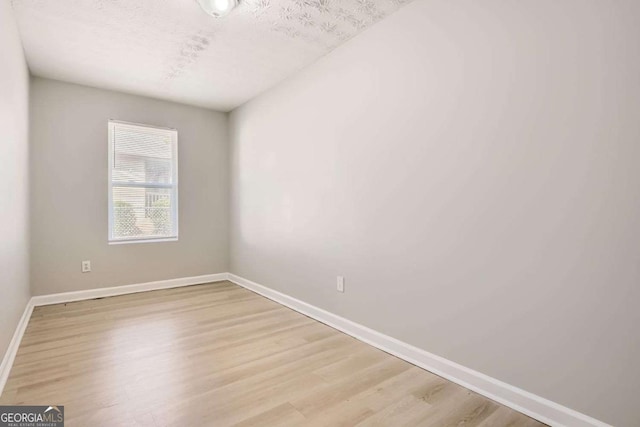 unfurnished room with a textured ceiling and light hardwood / wood-style floors