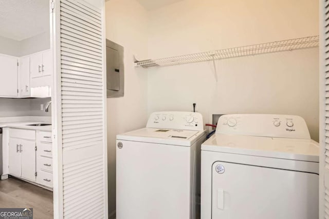 laundry area with sink, electric panel, washing machine and dryer, and hardwood / wood-style floors