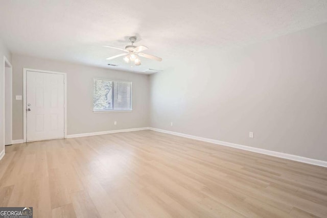 spare room with light wood-type flooring, baseboards, and ceiling fan