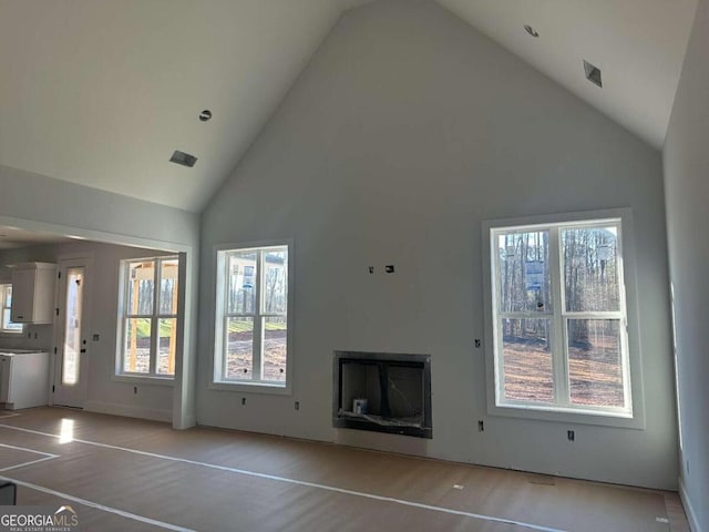 unfurnished living room featuring high vaulted ceiling and light wood-type flooring