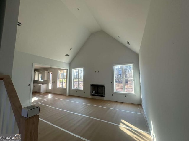 unfurnished living room featuring high vaulted ceiling and light hardwood / wood-style floors