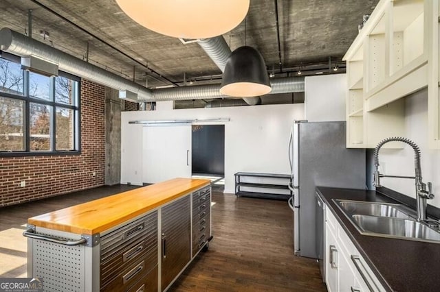 kitchen with sink, white cabinetry, wooden counters, dark hardwood / wood-style floors, and brick wall