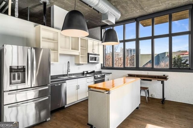 kitchen with sink, stainless steel appliances, white cabinets, dark hardwood / wood-style flooring, and decorative light fixtures