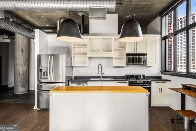 kitchen with butcher block countertops, sink, dark wood-type flooring, appliances with stainless steel finishes, and a kitchen island