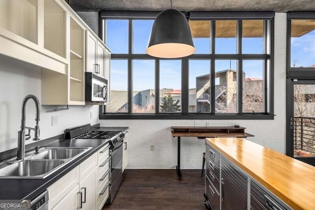 kitchen featuring dark hardwood / wood-style floors, sink, white cabinets, hanging light fixtures, and gas range oven