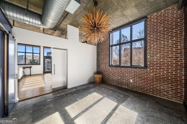 empty room with a high ceiling and brick wall