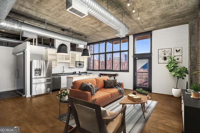 living room featuring dark hardwood / wood-style flooring, sink, track lighting, and a high ceiling