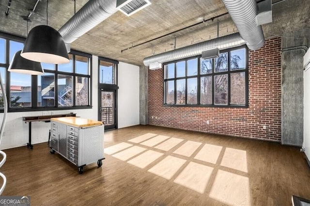 interior space with hardwood / wood-style flooring, brick wall, and a healthy amount of sunlight