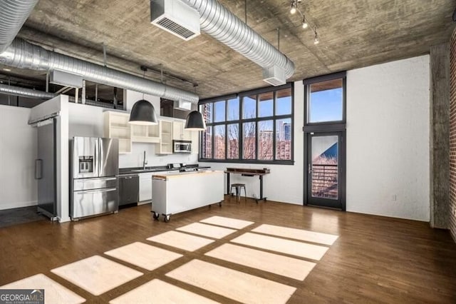 kitchen featuring hardwood / wood-style flooring, appliances with stainless steel finishes, hanging light fixtures, a center island, and white cabinets