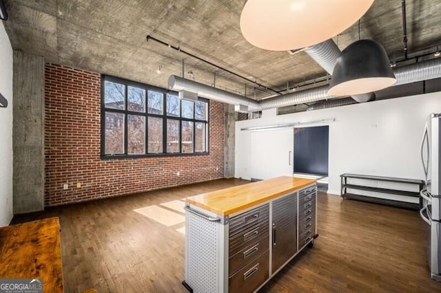 kitchen featuring wood counters, brick wall, dark hardwood / wood-style floors, and dark brown cabinets