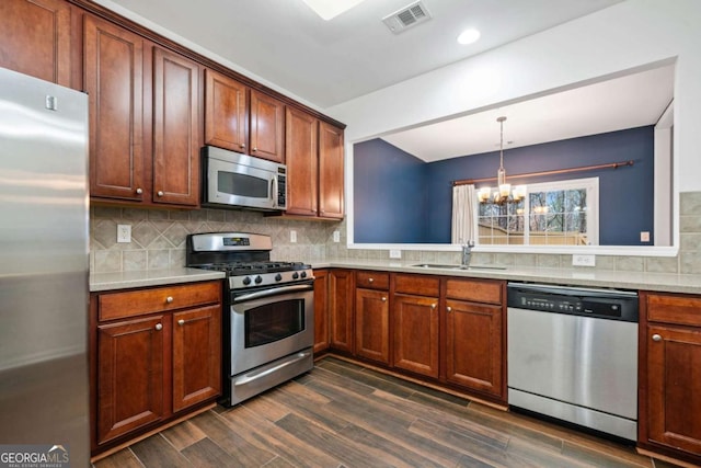 kitchen with sink, decorative light fixtures, appliances with stainless steel finishes, dark hardwood / wood-style flooring, and backsplash