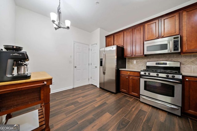 kitchen featuring pendant lighting, backsplash, stainless steel appliances, and dark hardwood / wood-style floors